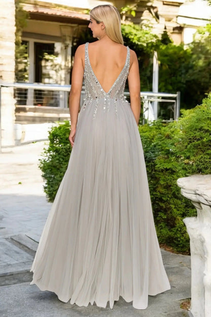 A full back view of a woman wearing a silver formal dress with an open V-back and flowing skirt.