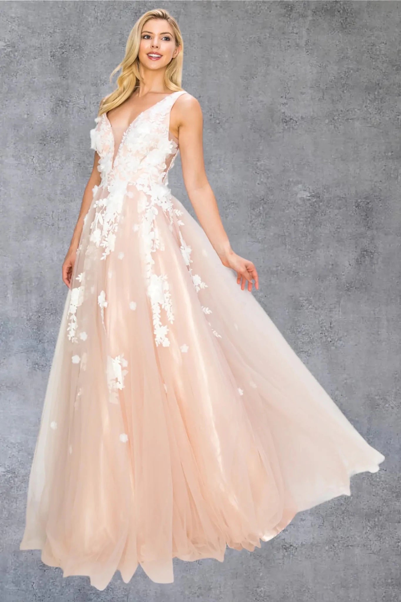 A full-length front view of a woman wearing a blush formal dress featuring a deep V-neckline and flowing skirt.