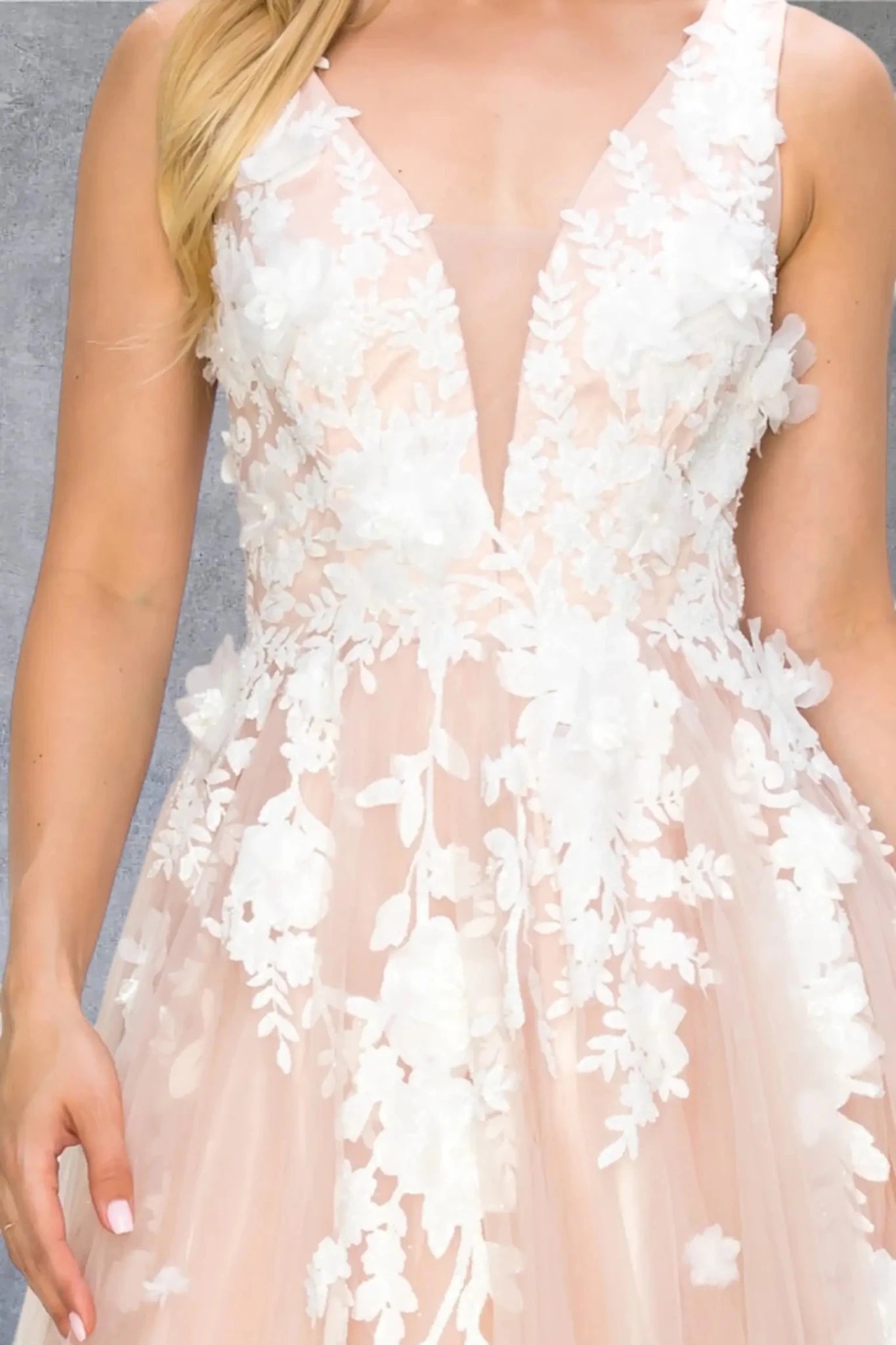 Close-up of blush lace bodice with pearl beads and organza floral detail.