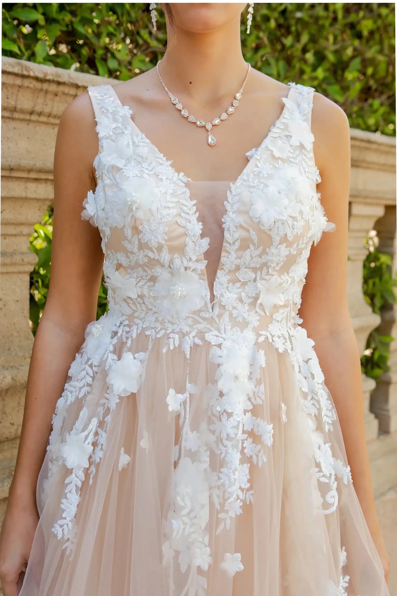 A close-up view of a woman wearing a champagne lace bodice with pearl beads and 3D organza floral detail.