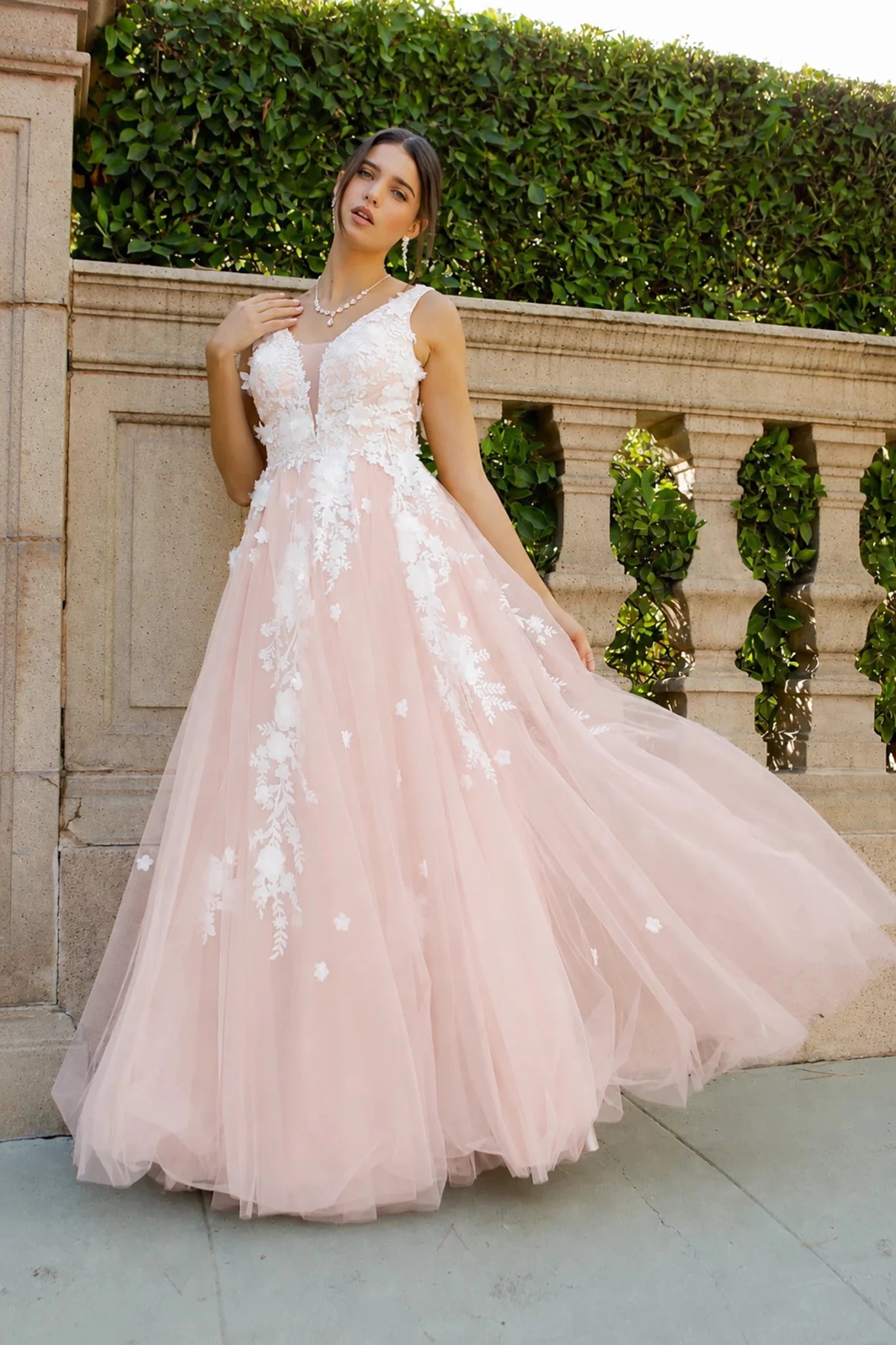 A woman wearing a blush pink tulle gown with 3D floral appliqués