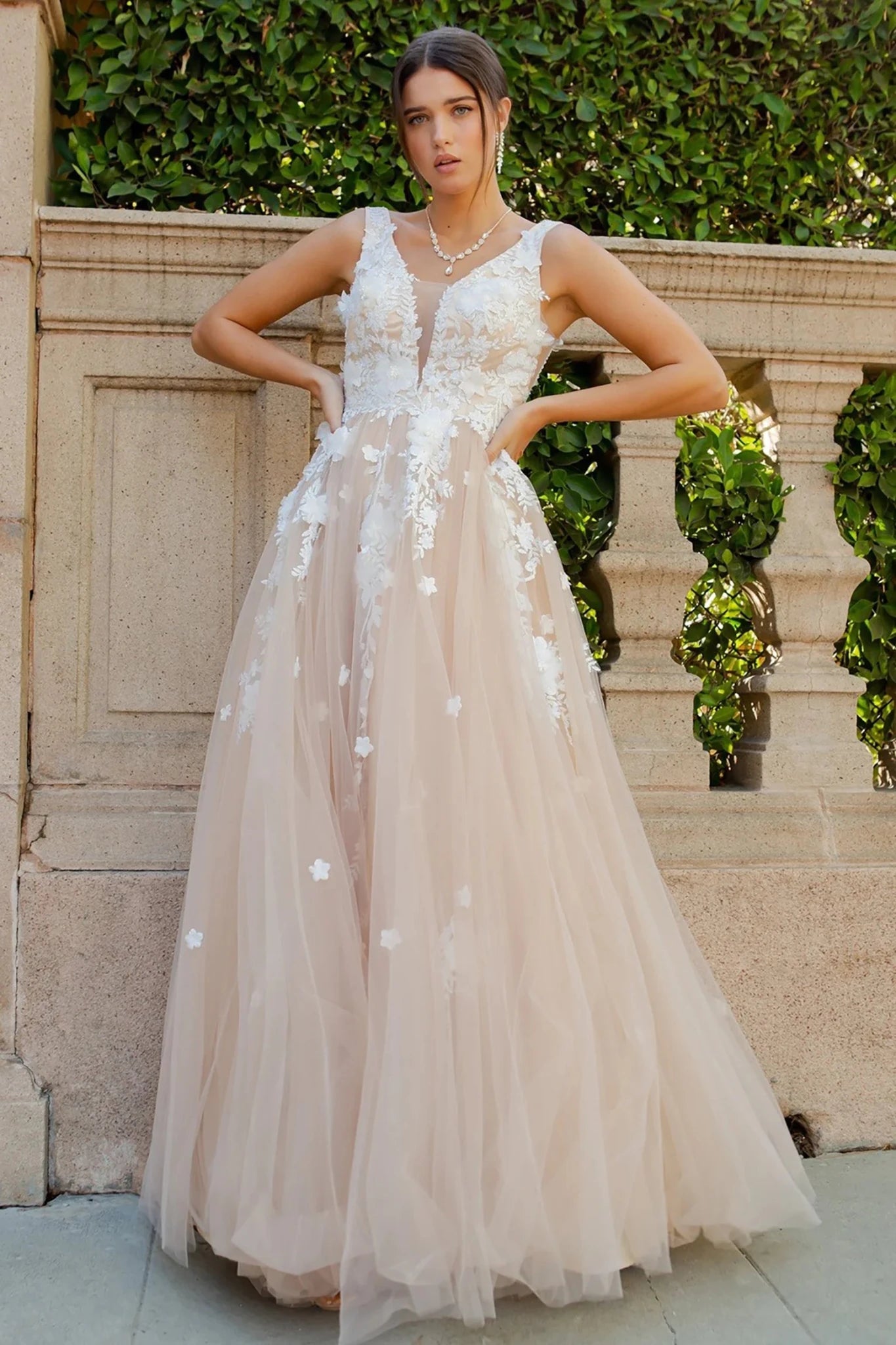 a sleeveless A-line champagne gown with white floral appliqués, deep V-neckline and tulle skirt 