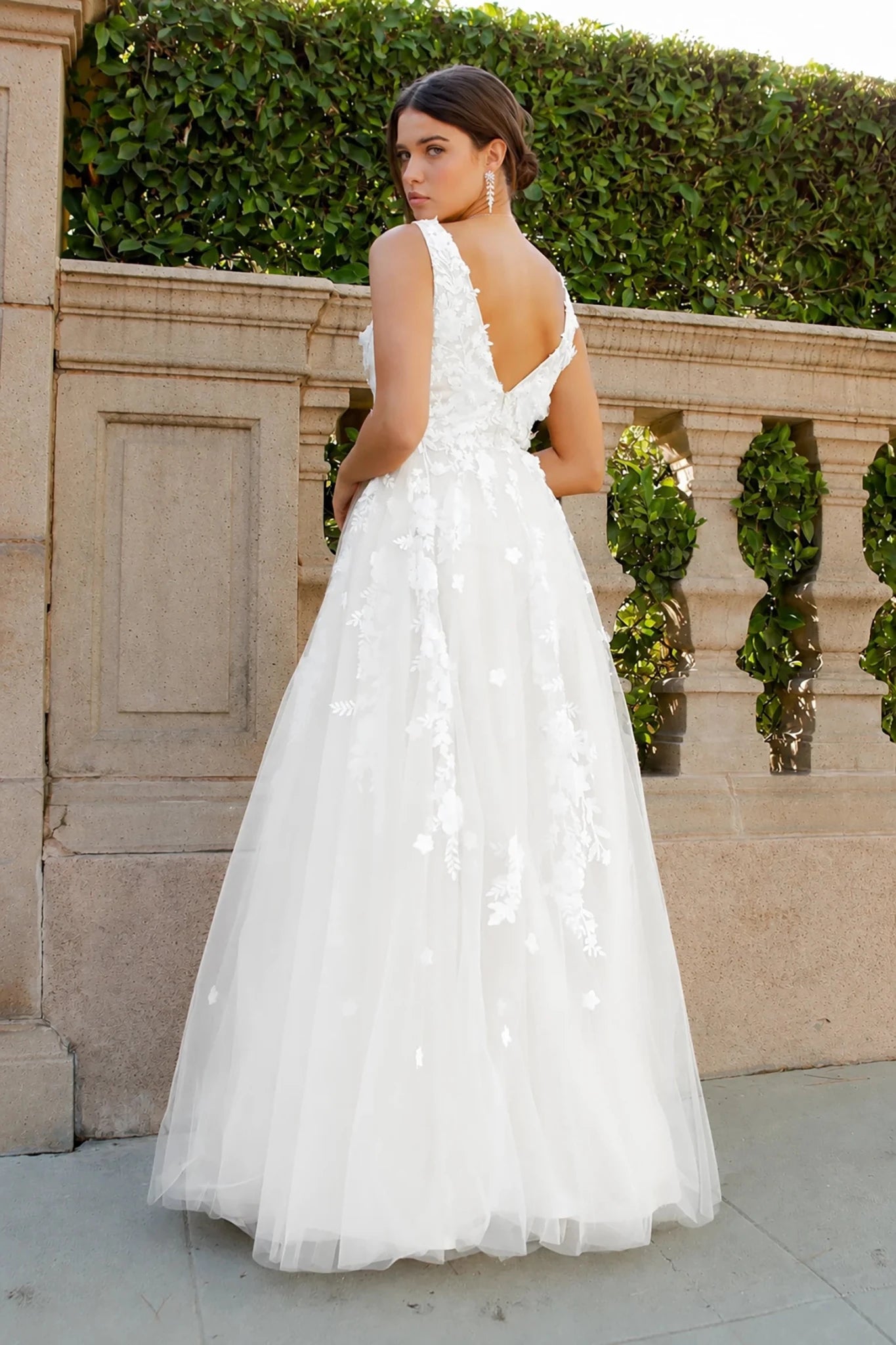 A woman wearing a white dress gown with 3D floral appliqués and v back