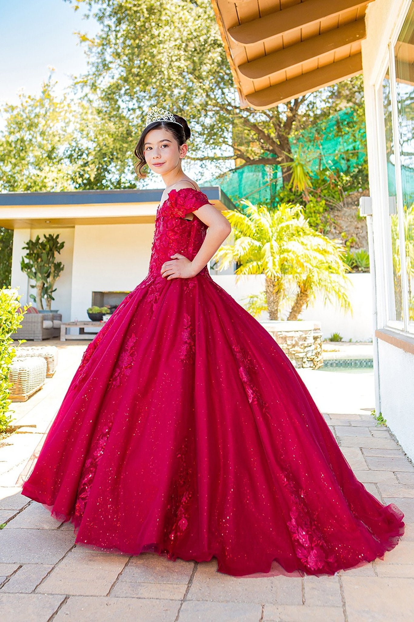 Red side view kids mini quinceañera mini quince dress with sweetheart neckline, glitter lace fabric, 3D floral sequin applique and train.