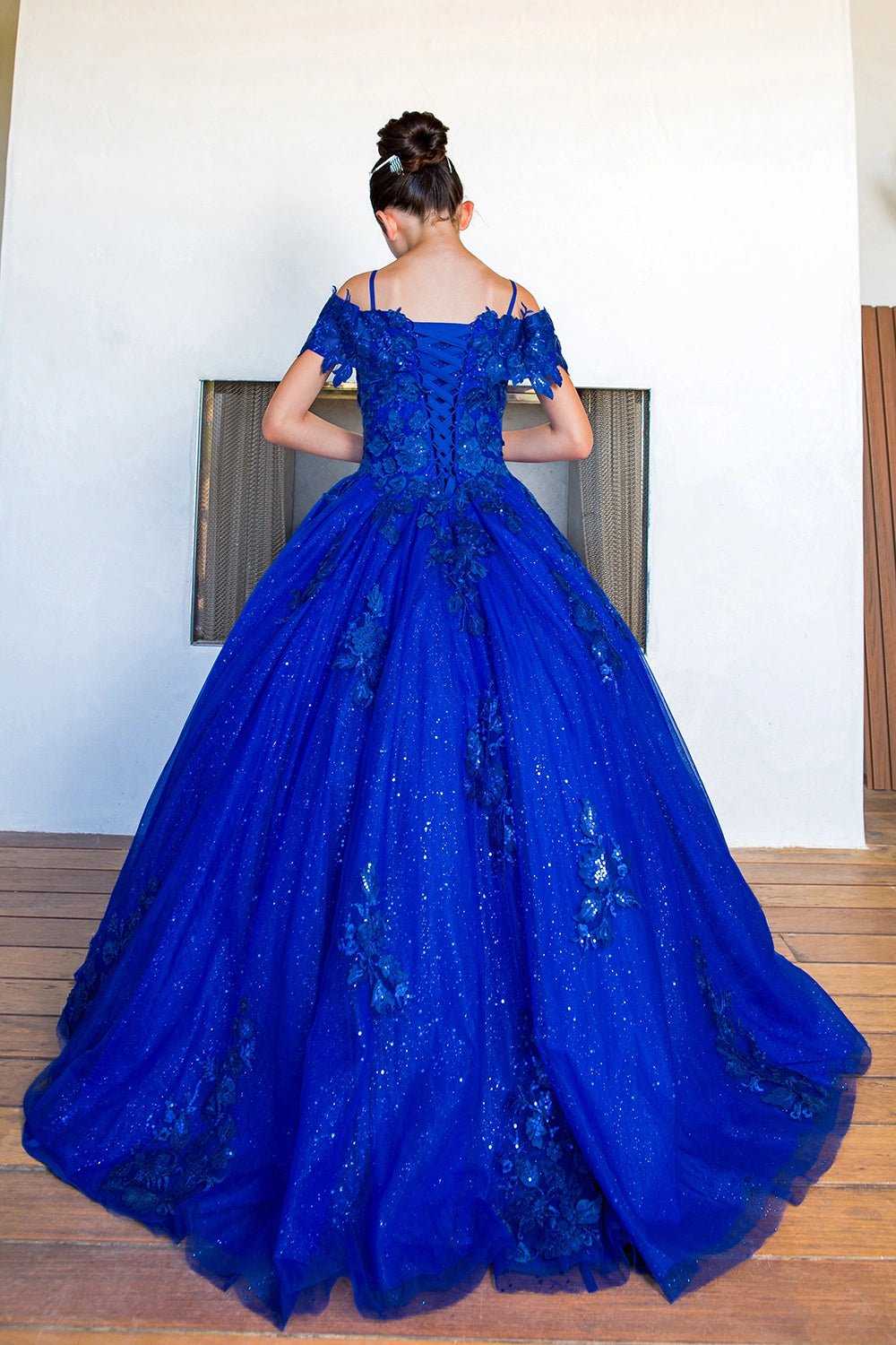 Displayed in a back view, the Royal Blue mini quince dress has lace-up back and floral glitter train.
