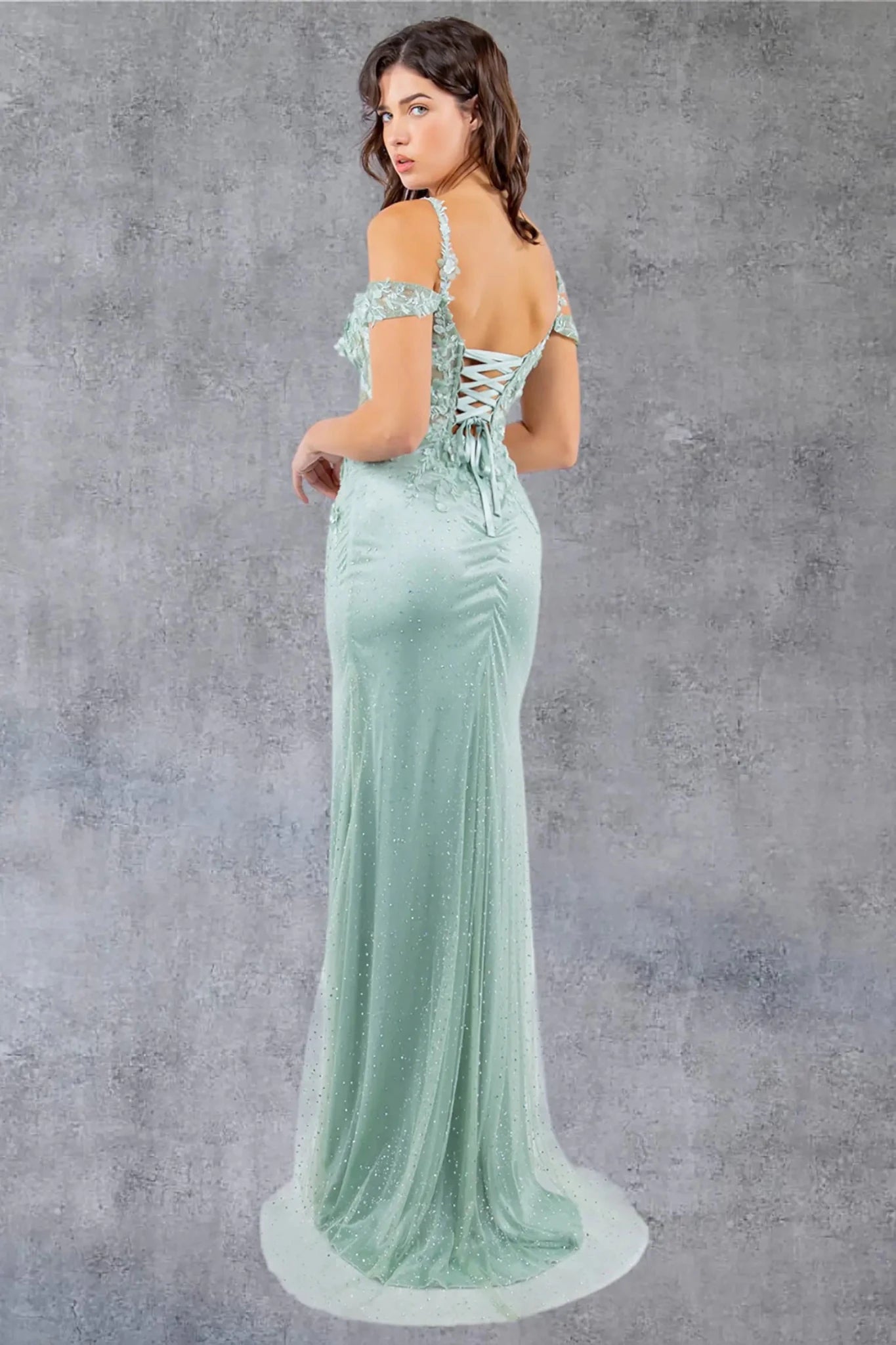 A full back view of a woman wearing a sage formal dress styled with a lace-up corset closure.