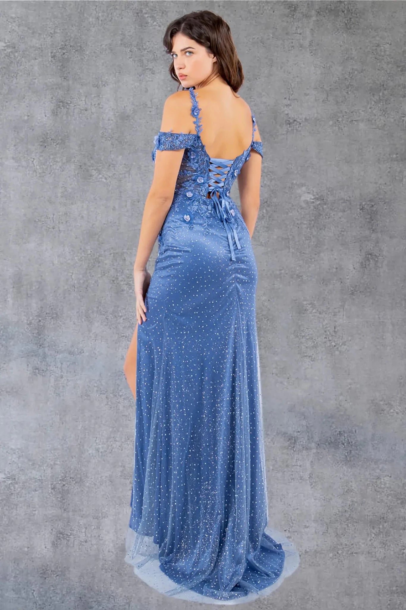A full back view of a woman wearing a blue formal dress with a lace-up corset and detachable sleeves.