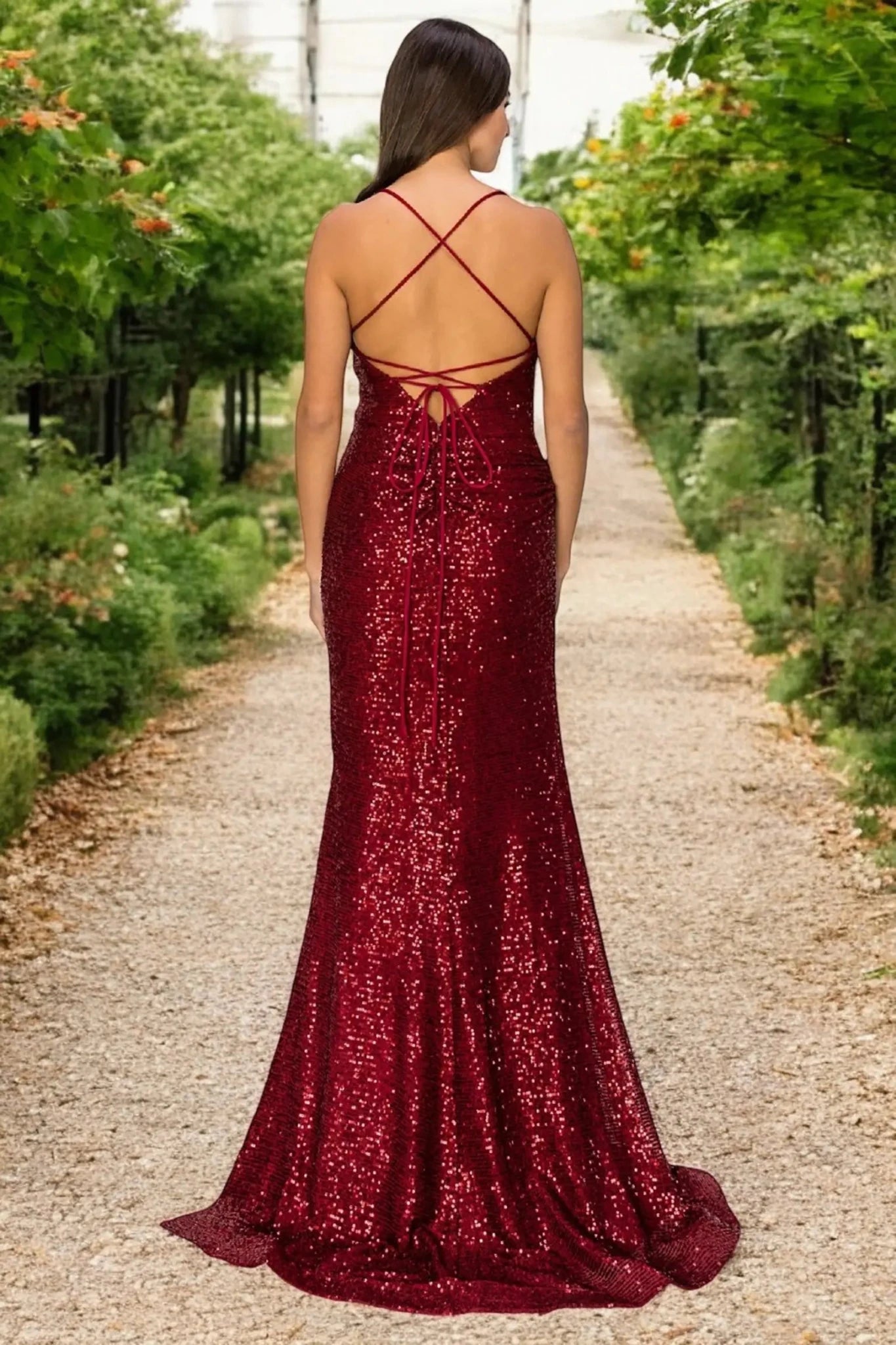 A full-length view of a woman wearing burgundy formal prom dress with lace-up corset closure.