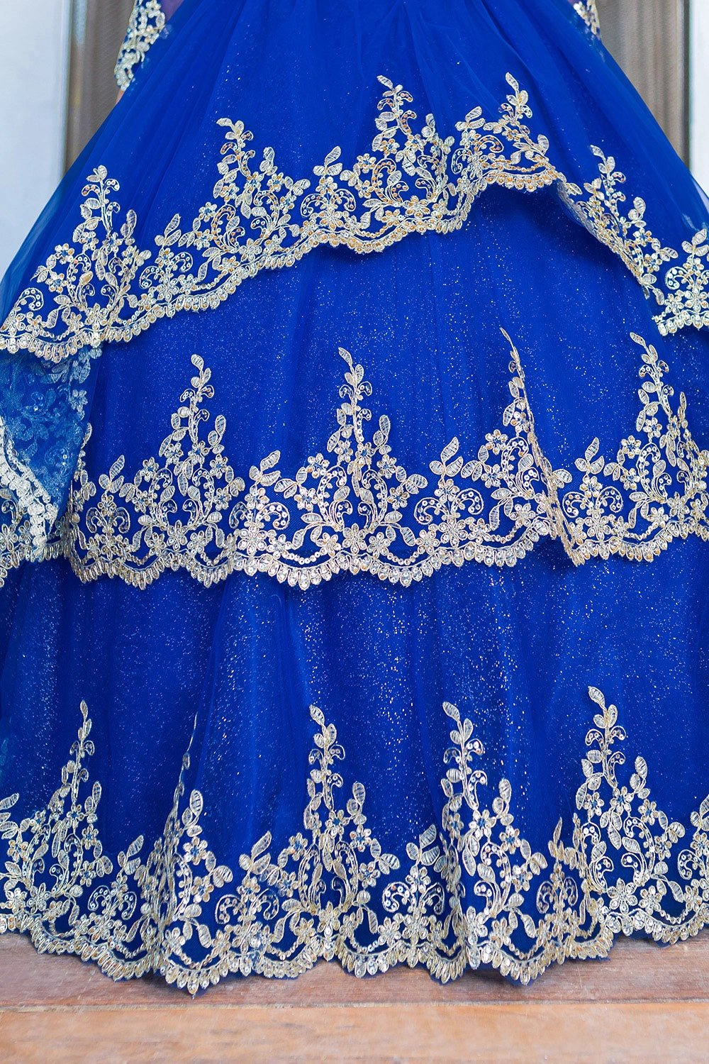 Presented in a skirt detail, the Royal Blue mini quince dress has gold lace borders across the layered tulle skirt.