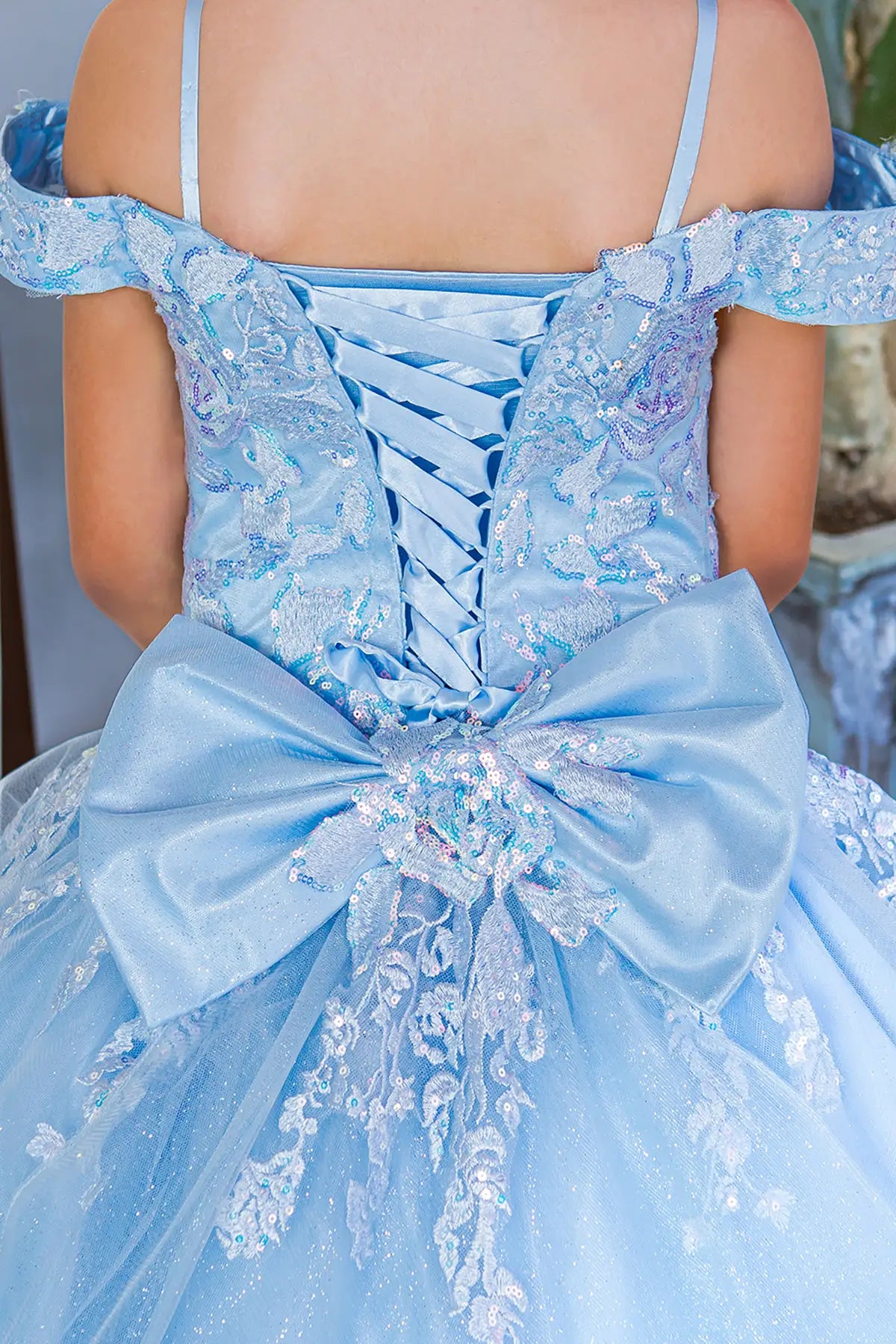 Light blue front view kids mini quinceañera mini quince dress with off-shoulder lace, floral applique and large bow detail.