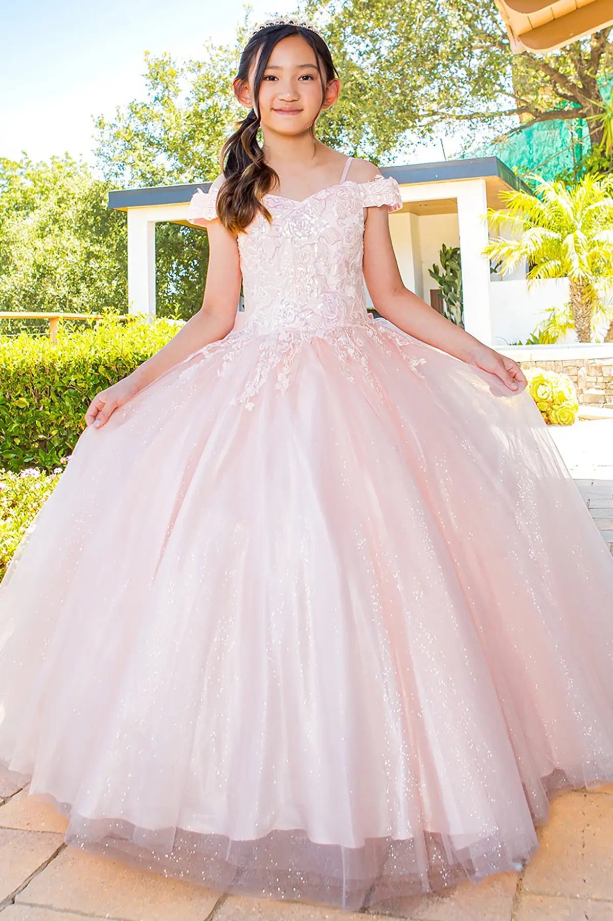 Blush front view kids mini quinceañera mini quince dress with floral lace, off-shoulder top and layered tulle skirt.