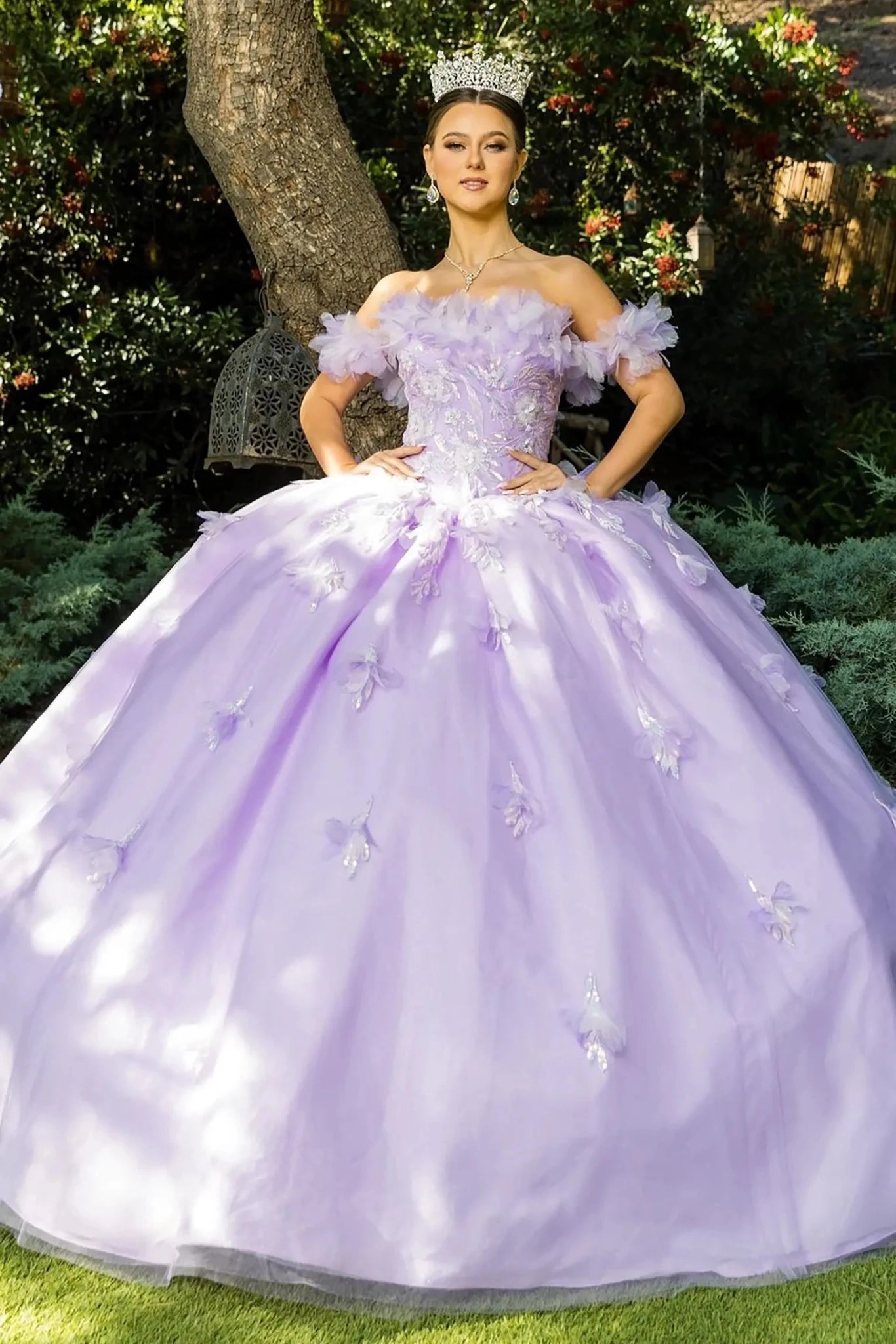 Front view of a woman wearing a lilac quinceanera dress with rainbow embroidery, sequin ruffle flowers, and crown detail