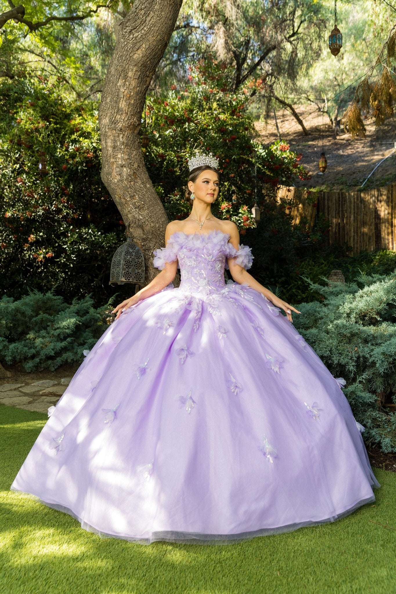 Front view of a woman wearing a lilac quinceanera dress with rainbow embroidery, sequin ruffle flowers, and hands at sides