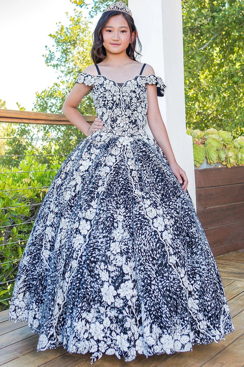 Shown in a front view, the Black mini quince dress has contrasting floral lace, off-shoulder sleeves and a full ball skirt.