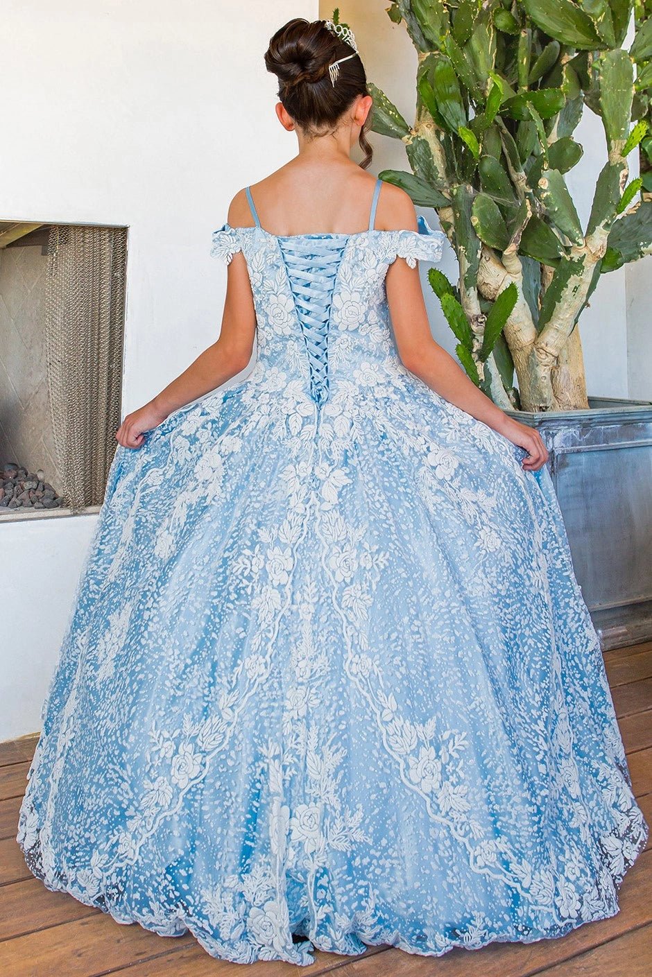 Displayed in a back view, the Blue mini quince dress has lace-up back and allover floral lace skirt.