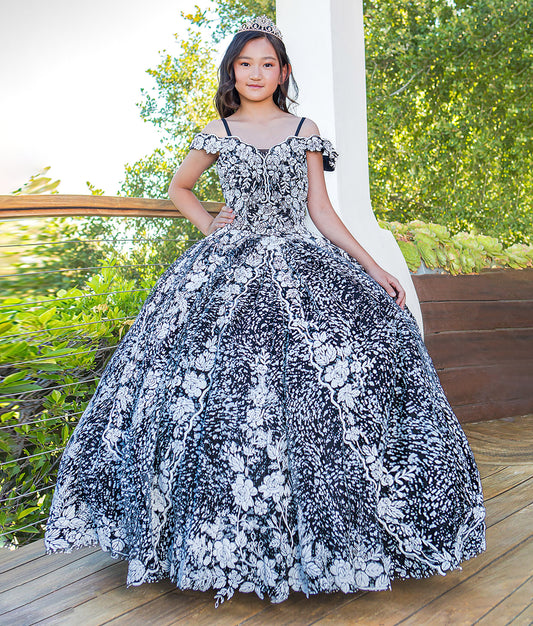Young girl in a black and white floral dress standing outdoors on a wooden deck.