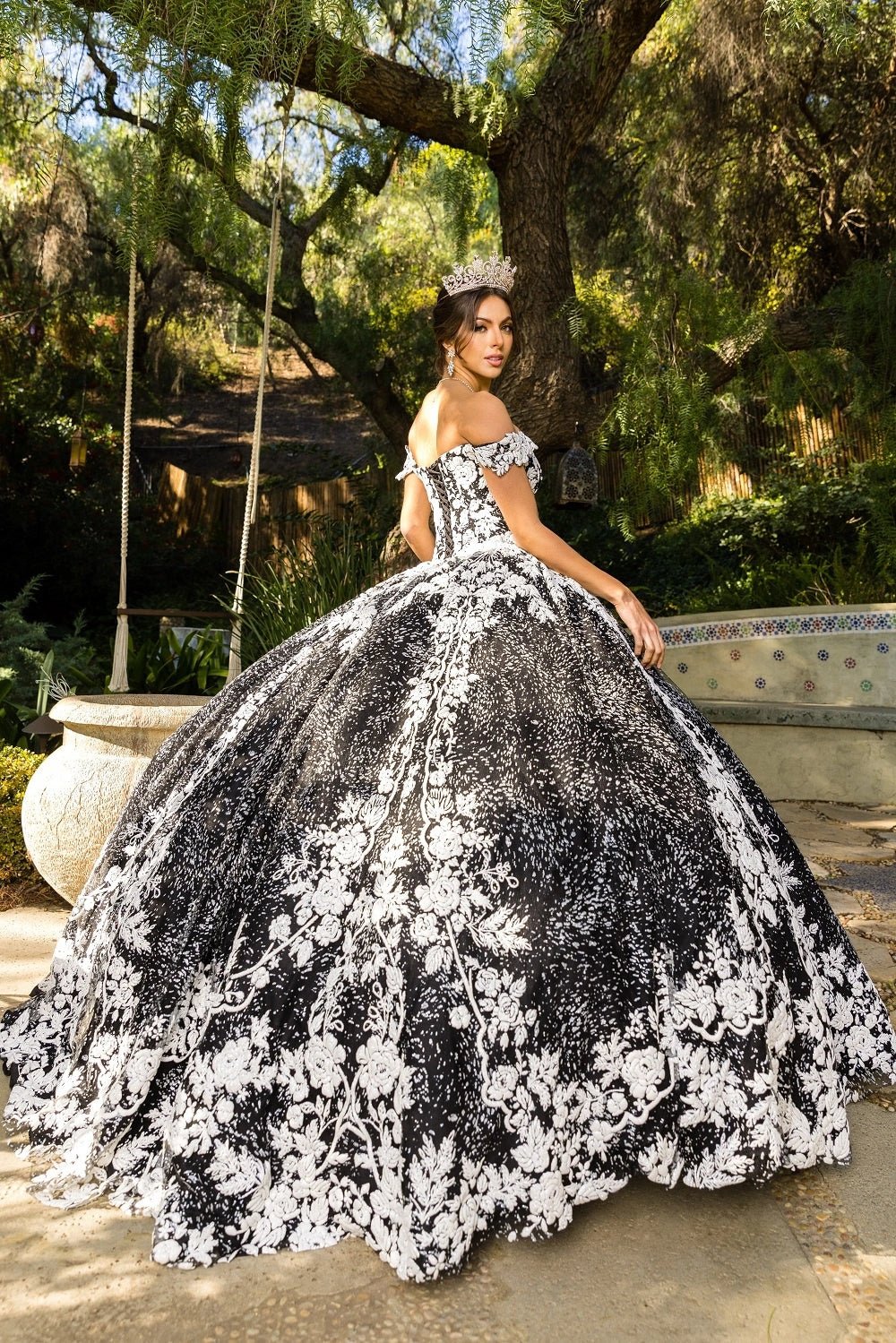 Viewed in a angled view, the Black quinceañera dress has off-shoulder neckline and contrasting lace skirt border.