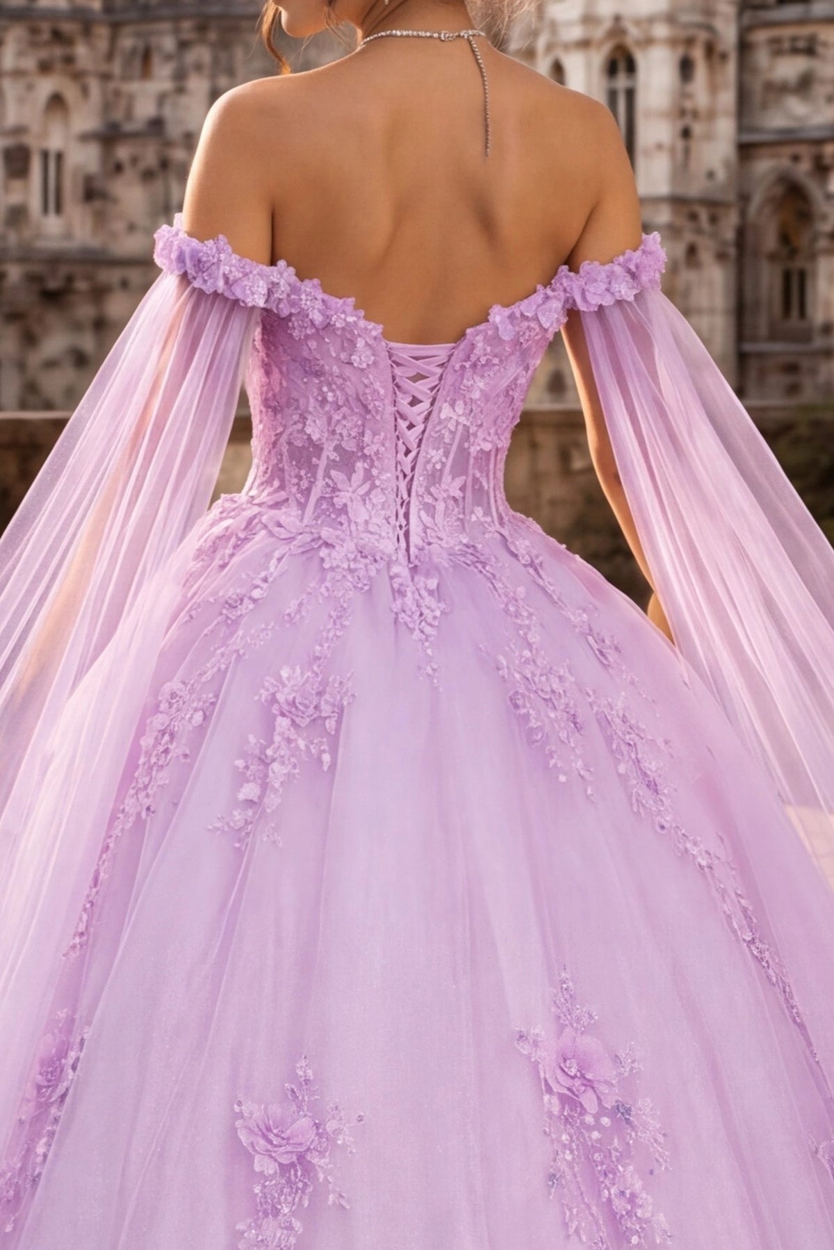 A lavender off-the-shoulder ball gown with a lace-up open back and sheer cape sleeves