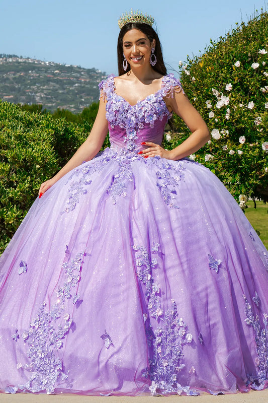 Woman in a purple floral dress standing outdoors with greenery and flowers in the background