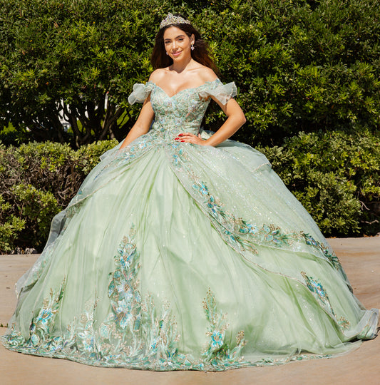 Woman in a green floral gown standing outdoors with greenery in the background