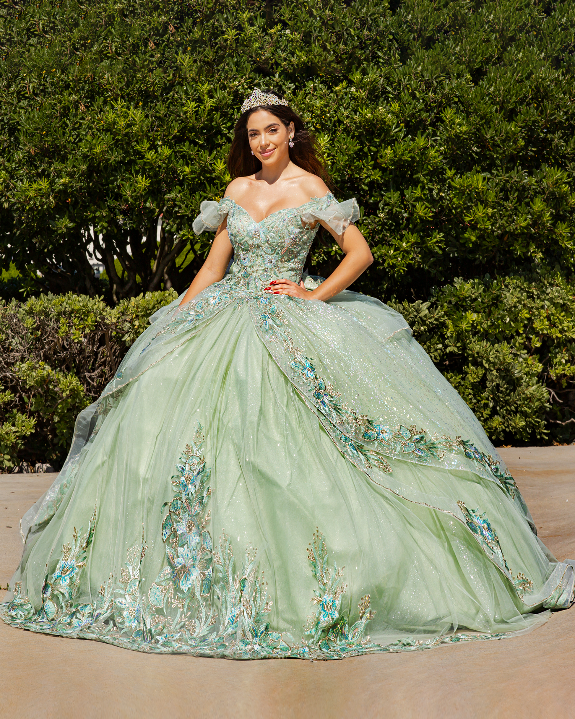 Girl in a sage green floral quince dress standing outdoors with greenery in the background