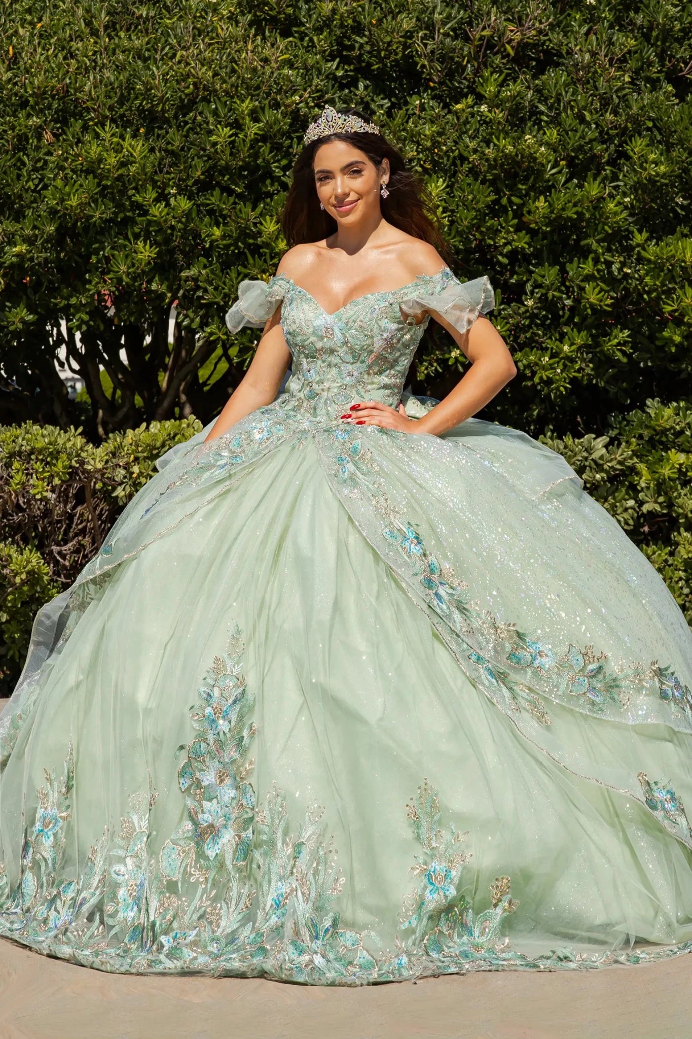 Woman in a sage floral quince ball gown standing outdoors with greenery in the background