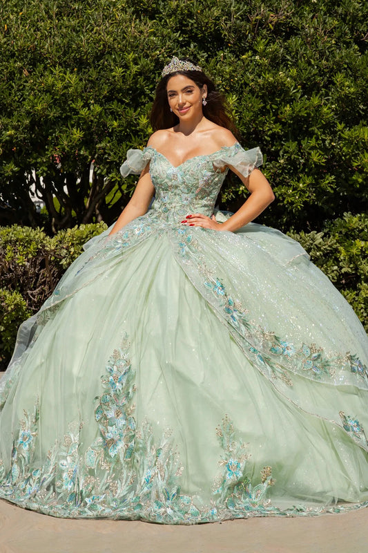 Woman in a sage floral quince ball gown standing outdoors with greenery in the background