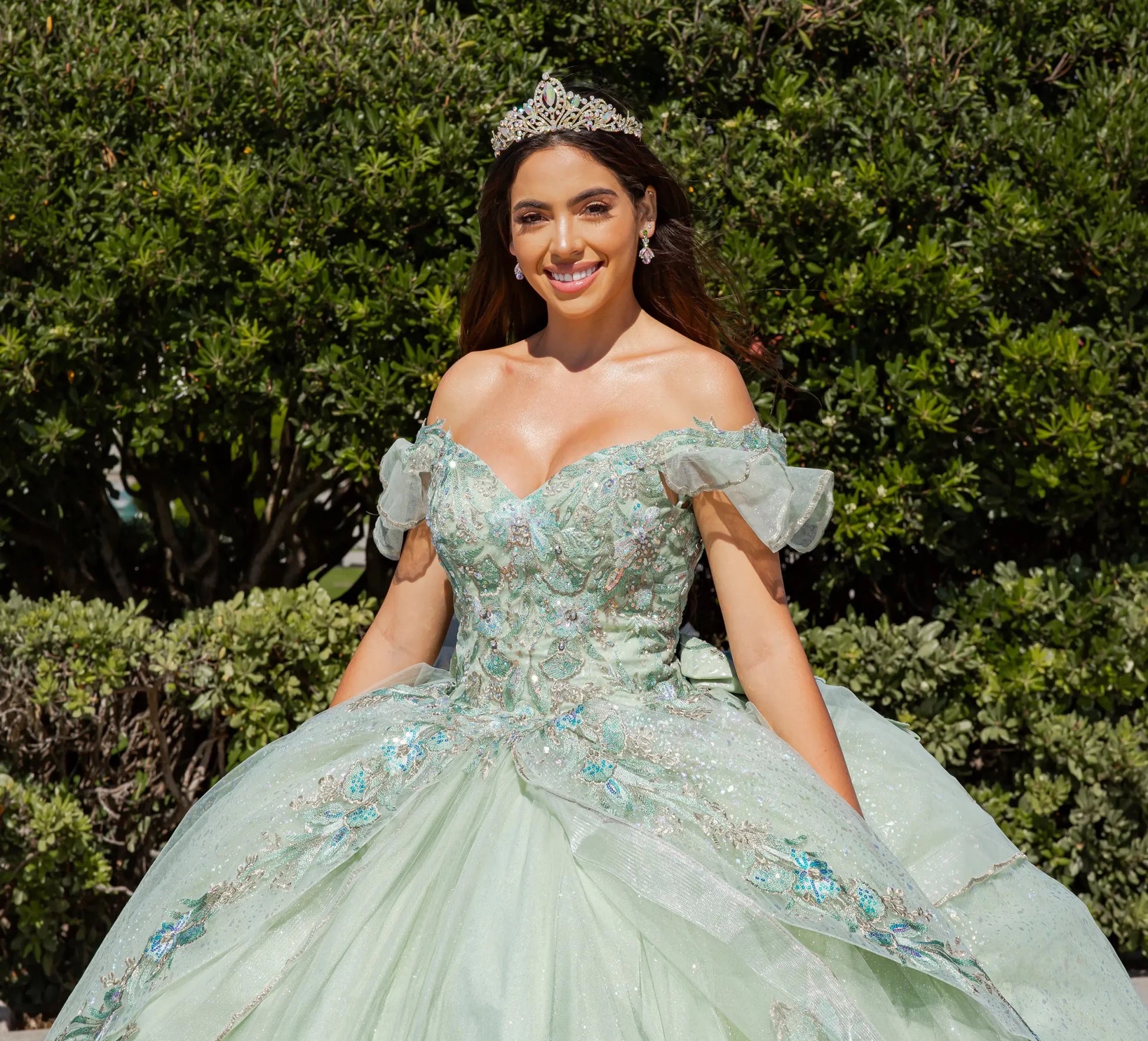Woman in a light green formal gown with floral details outdoors.
