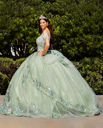 Girl in a sage green floral quince dress with floral details standing in front of green bushes.
