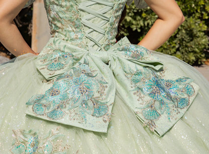 Close-up of a light green dress with floral embroidery and a large bow.