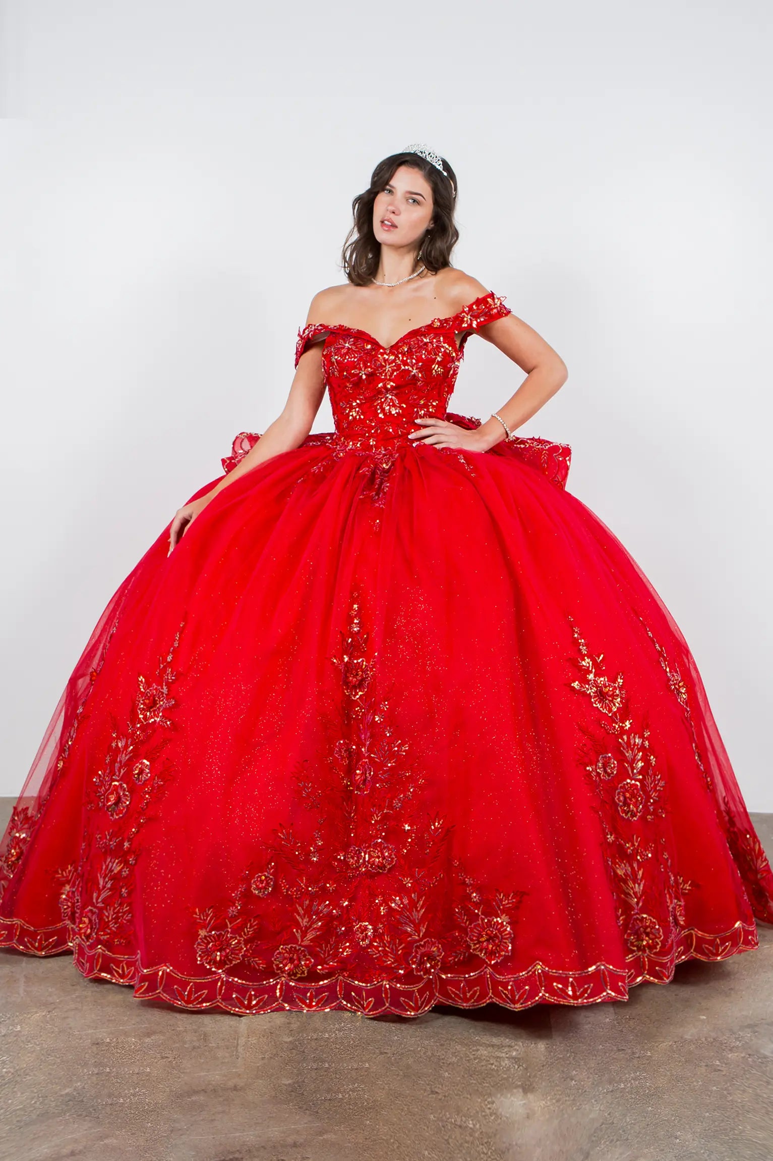 Woman wearing a red quinceanera ball gown with gold floral embroidery 