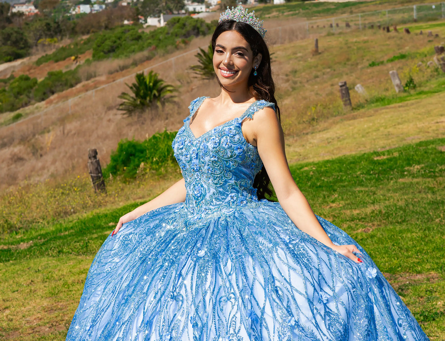 Woman in a blue dress with floral details sitting on grass