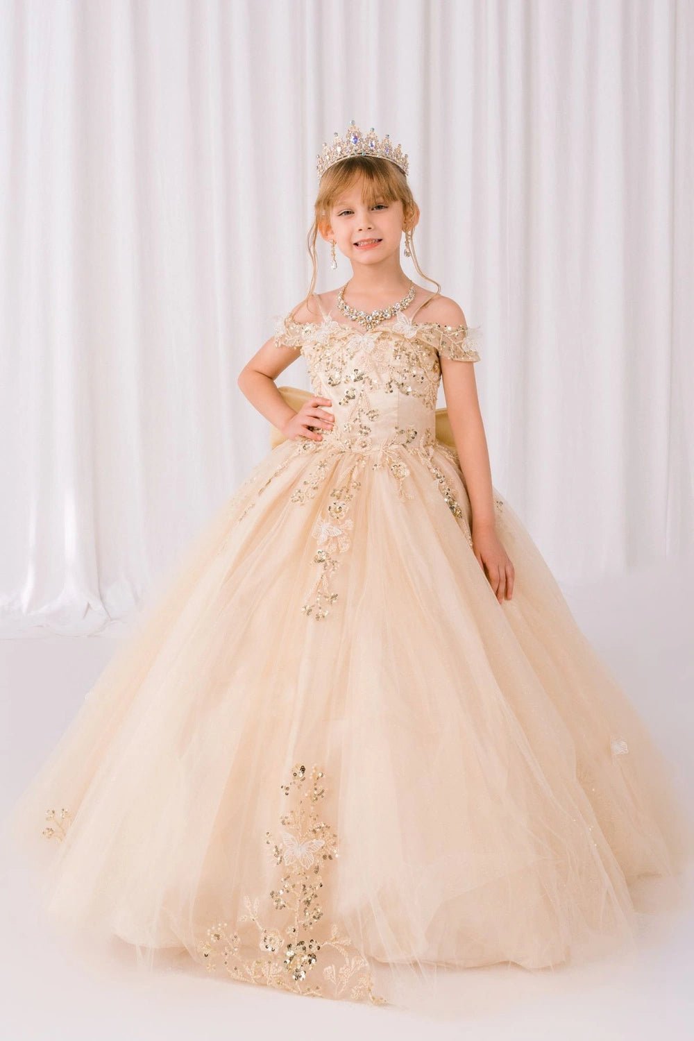Shown in a front view, the Champagne mini quince dress has off-shoulder floral bodice and floral appliques across the skirt.