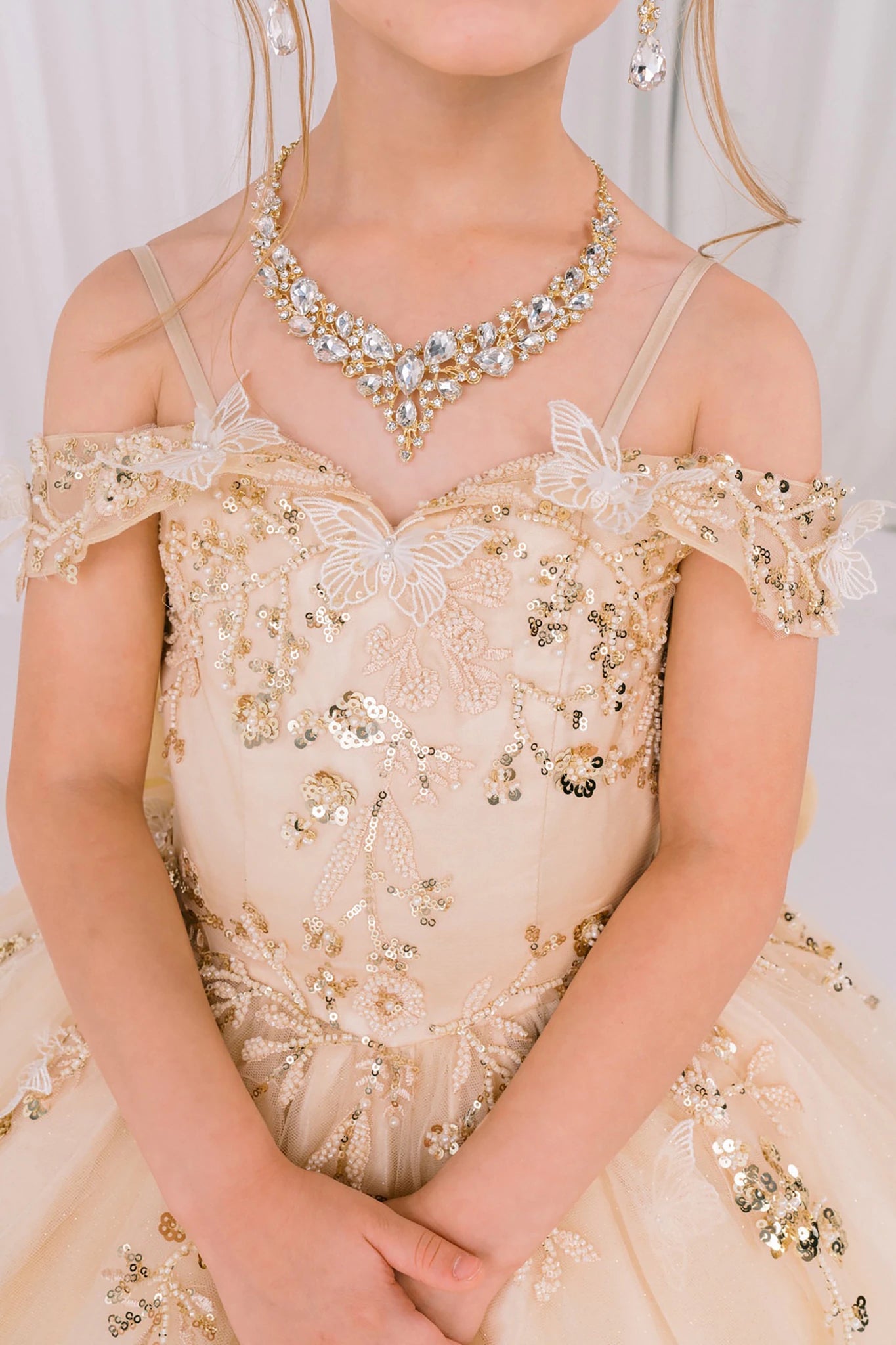 Champagne front view kids mini quinceañera mini quince dress with floral lace, gold detailing and glitter tulle skirt.