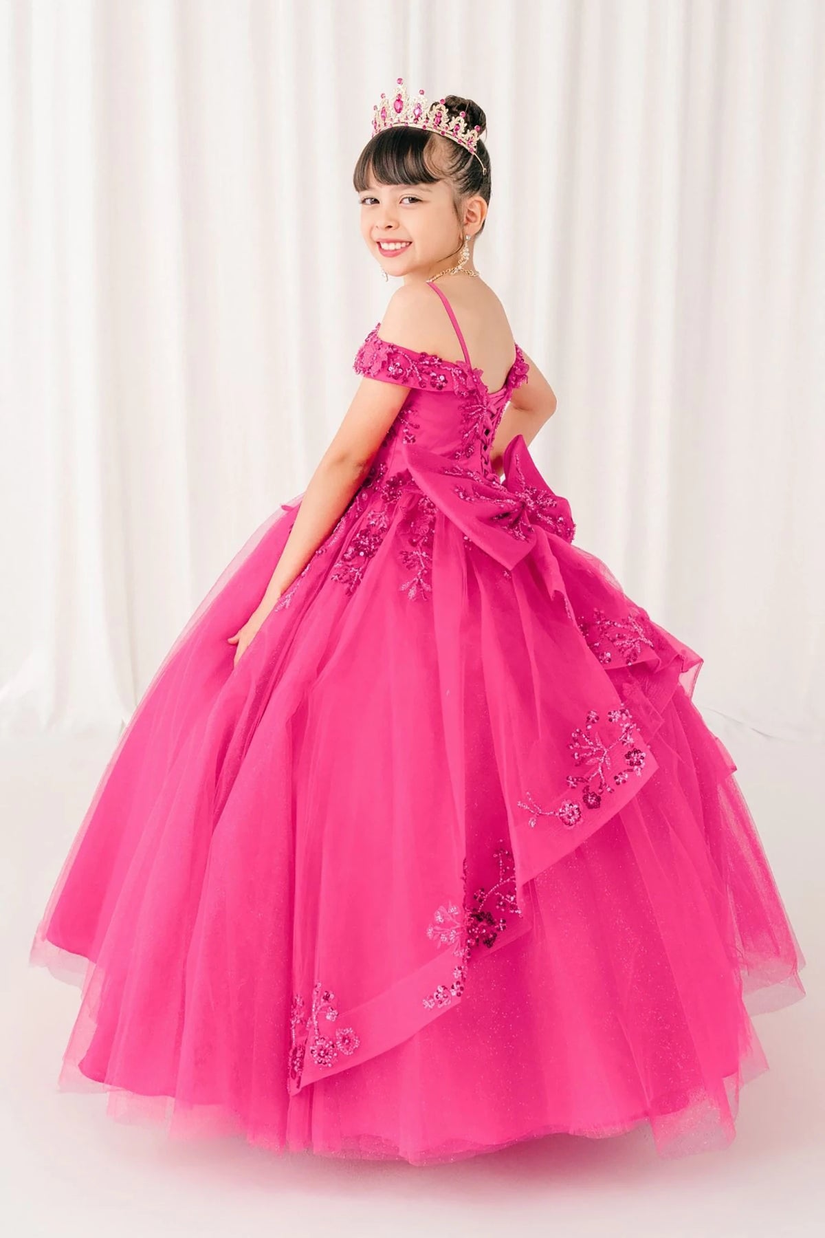 Detailed view highlights fuchsia kids mini quinceañera mini quince dress with bead embroidery and glitter tulle sweep train.