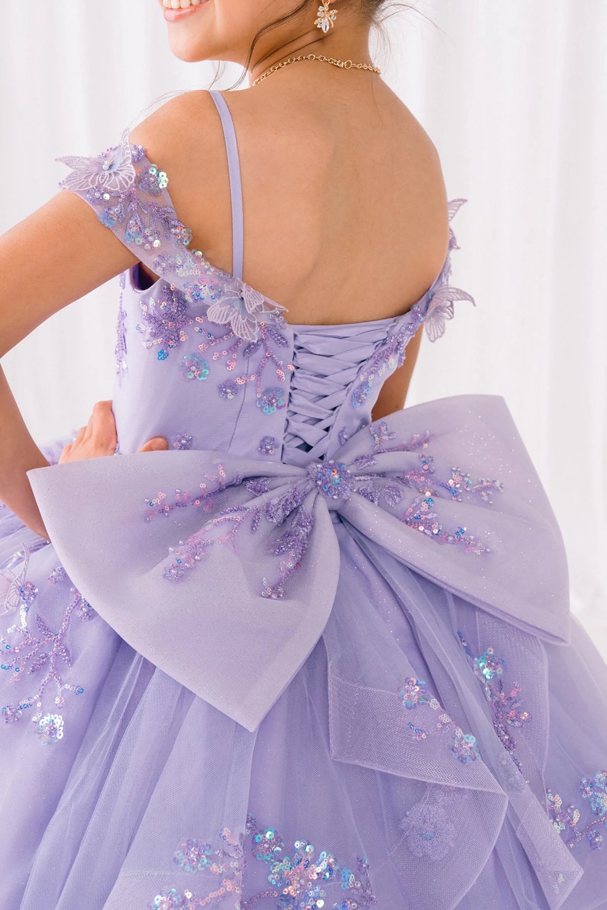 Lilac front view kids mini quinceañera mini quince dress with bead embroidered butterfly applique, bow detail and sweep train.