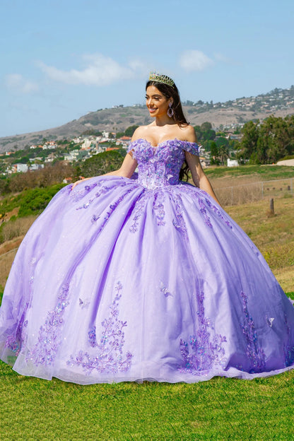 A woman in a lilac quinceañera dress densely adorned with 3D butterfly and floral appliqués, standing outdoors.