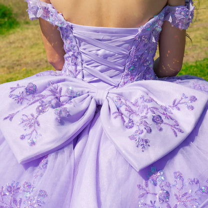 close up a lilac ball gown with floral embroidery and a large bow on a back of the dress