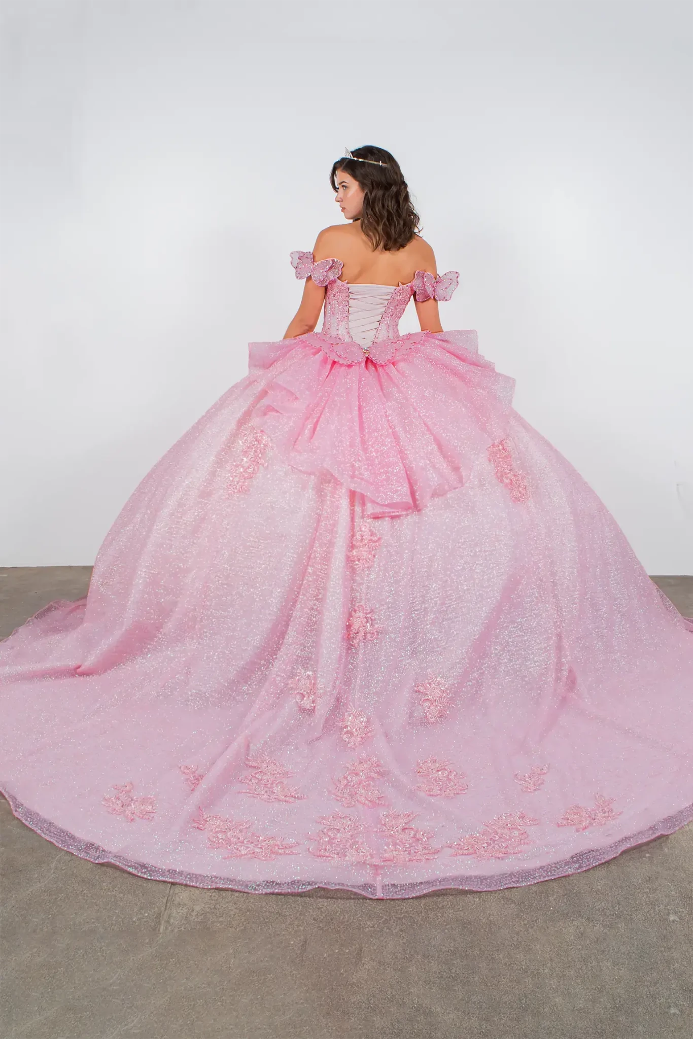 Pink quinceanera ball gown with floral details and butterfly big bow and long train 