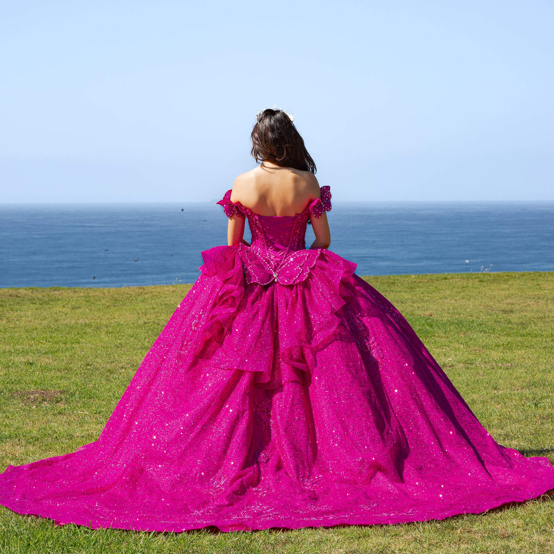 Person in a fuchsia gown standing on grass with ocean view