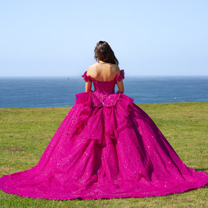 Person in a fuchsia gown standing on grass with ocean view