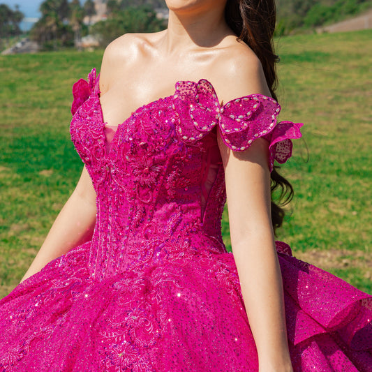 Person wearing a fuchsia, sparkly dress with a floral top in an outdoor setting.