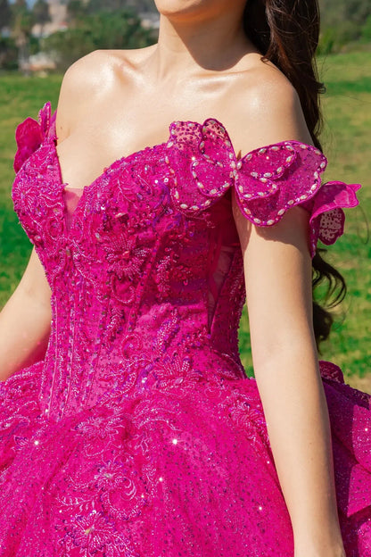 Woman standing close up in fuchsia hot pink ball gown with lace and sequin detailing, off-the-shoulder ruffled sleeves with butterfly
