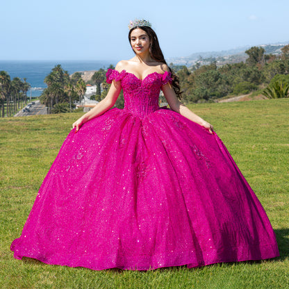 Woman in a fuchsia quinceañera dress standing on grass with ocean view