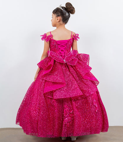 Young girl wearing a pink sparkly dress with ruffles on a white background