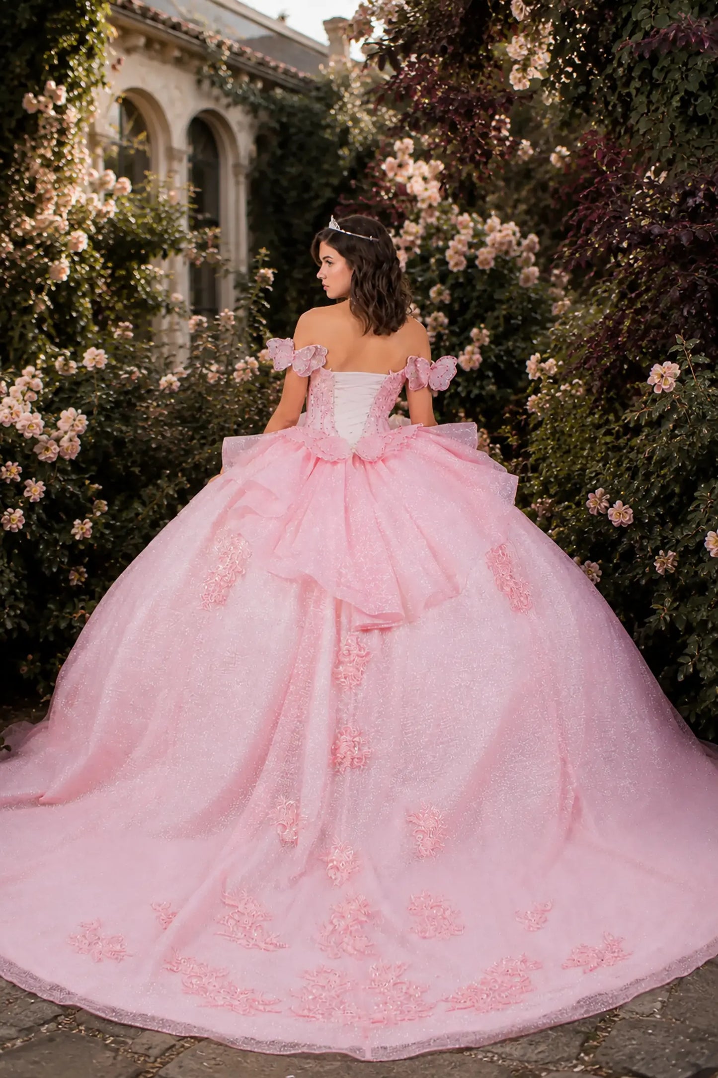 Pink quinceanera ball gown with floral details and butterfly big bow and long train 