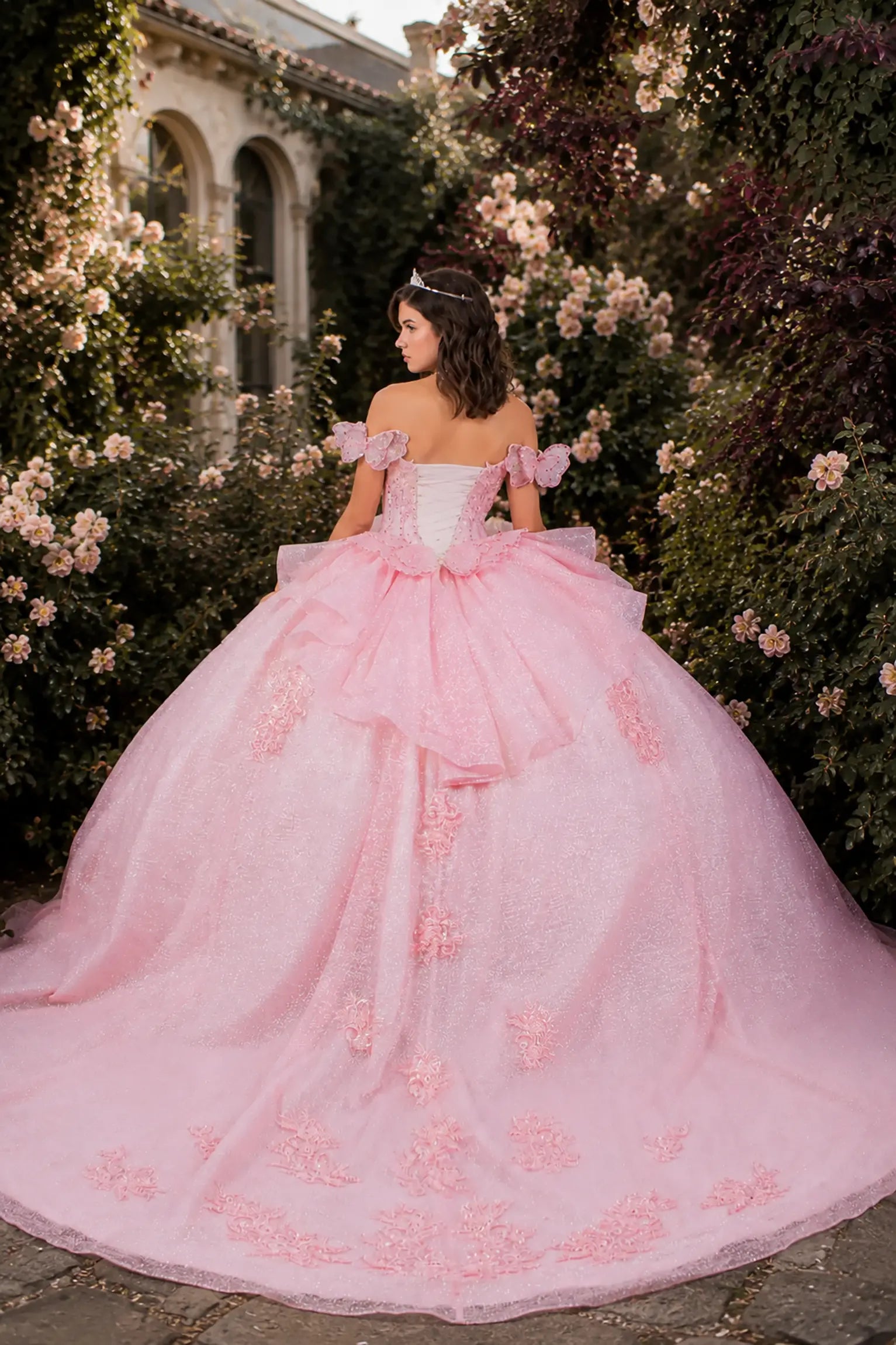 Pink quinceanera ball gown with floral details and butterfly big bow and long train 