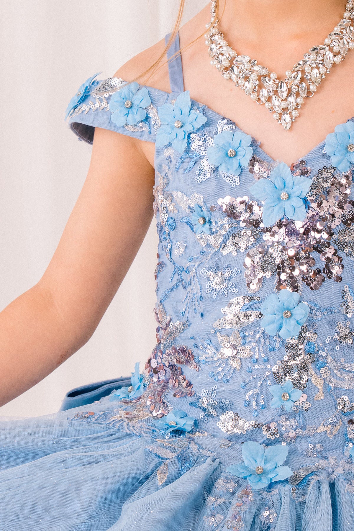 Light blue front view kids mini quinceañera mini quince dress with floral applique, sequin details and glitter tulle.