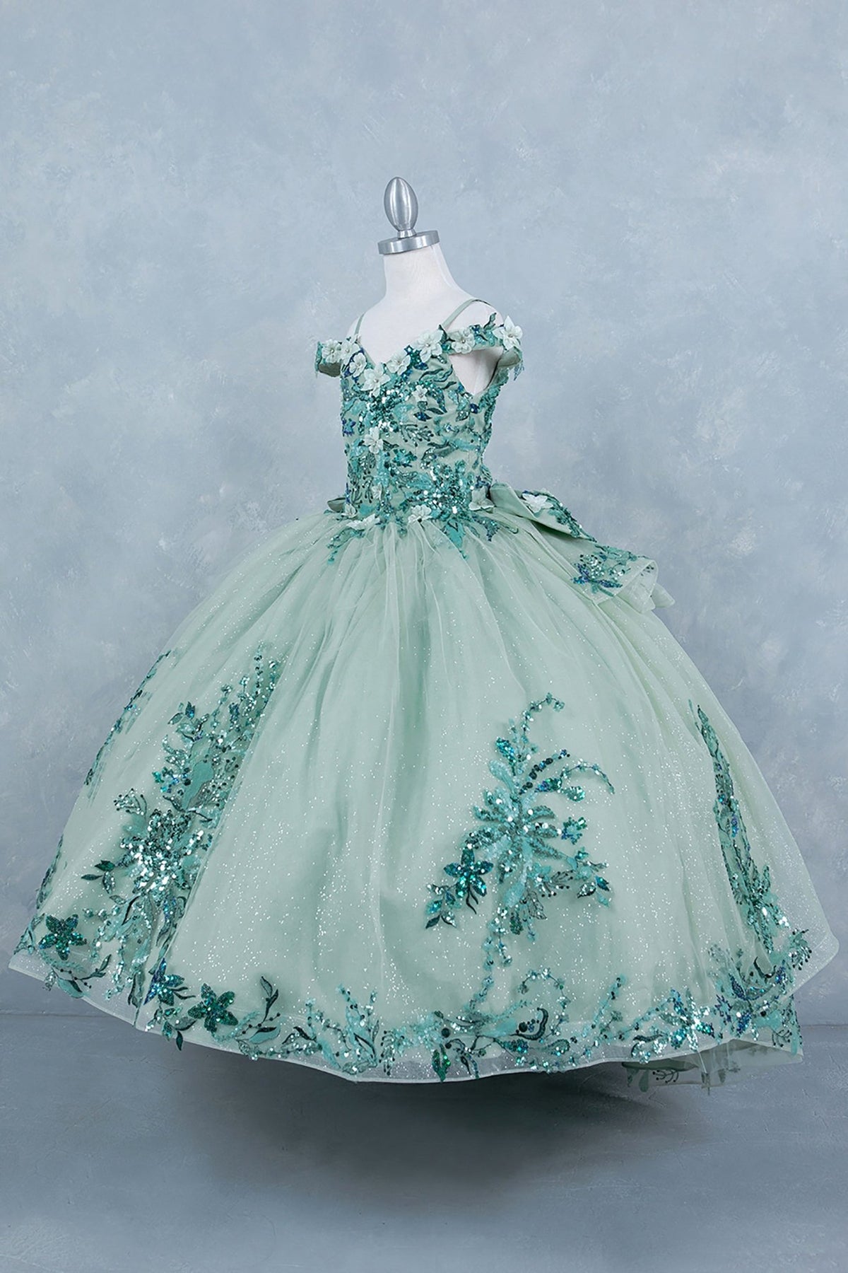 Sage side view kids mini quinceañera mini quince dress with off-shoulder 3D beaded floral applique, glitter tulle and train.