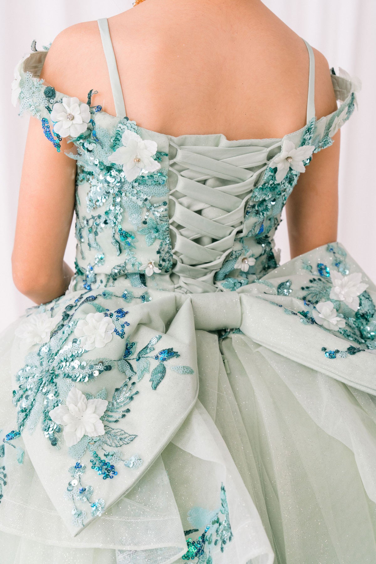 Sage front view kids mini quinceañera mini quince dress with floral lace embellishments and glitter tulle train.